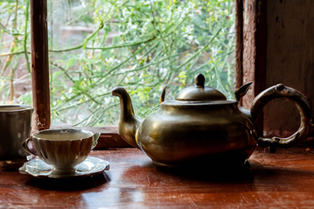 Antique copper teapot and a cup of tea at the windowの素材