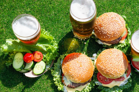 Burgers and glasses of beer on agreen grass lawnの素材