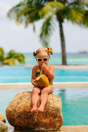 portrait of cute toddler girl with coconut cocktail in the tropical beachの写真素材