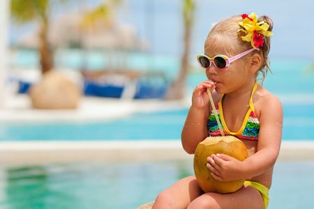 portrait of cute toddler girl with coconut cocktail in the tropical beachの写真素材