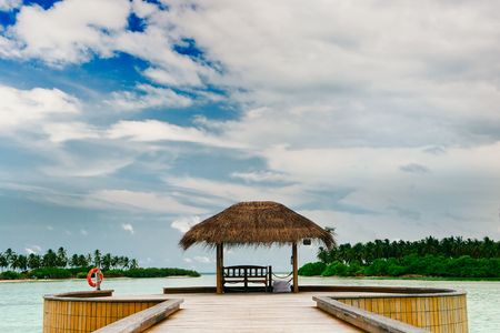 Wooden jetty leading to bungalow among turquoise ocean watersの写真素材