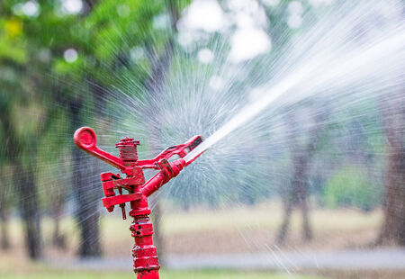 The red sprinkler spraying water in garden