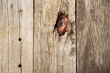 The human eye in wooden hole for hidden from scare conceptの写真素材