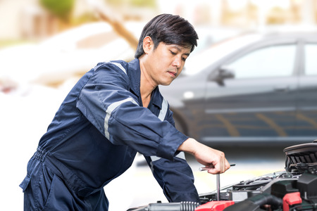 Motor vehicle mechanic man maintenance and checking the car engine in garageの写真素材