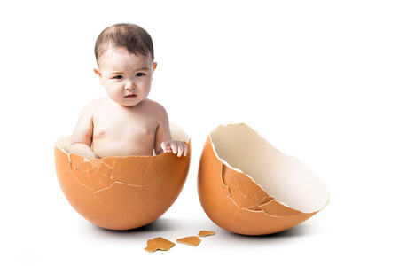 Little cute asian boy in broken egg shell in concept of new life isolated on white