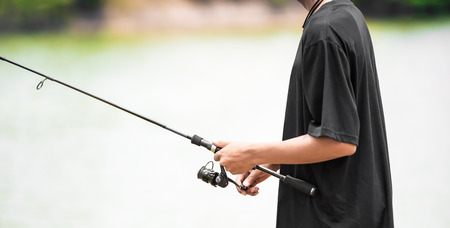 Closeup of the angler man hand fishing at the pond