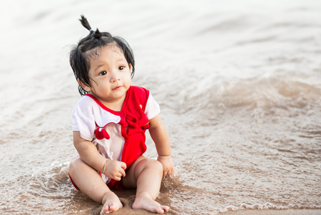 Cute asian little baby girl playing at the beachの写真素材