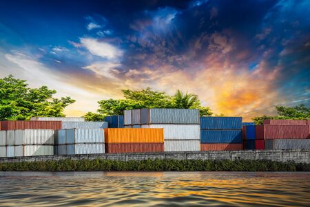 Stack of container at the riverside industrial estate on sunset backgroundの写真素材
