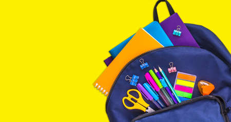 The concept of going back to school. Blue school bag with school supplies on a yellow background. Space for text. The view from the topの写真素材