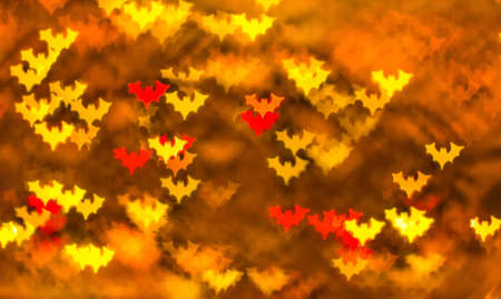 Abstract background for Halloween, bokeh in the form of bats in red, yellow and orange on a dark...