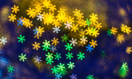 Abstract Christmas and new year bokeh background in the form of snowflakes in different colors on a...