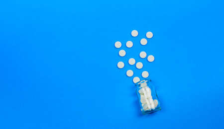 White tablets and a glass bottle on a blue background. Concept of healthcare and medicine. Flatley. The view from the top. Space for text.の写真素材