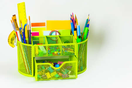Back to school. A variety of colorful office supplies in a green stand on a white background with...