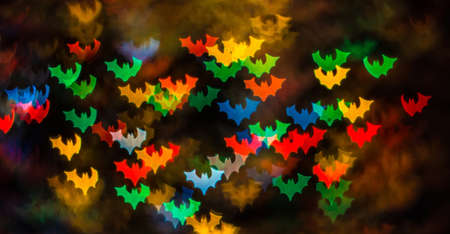 Abstract background for Halloween, bokeh in the form of bats in red, yellow, blue, green and orange on a dark background.の写真素材