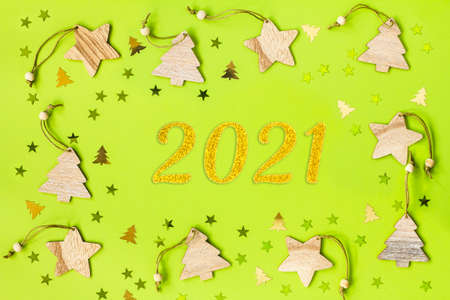 Wooden Christmas toys and confetti in the form of Christmas trees and stars on a green background,...