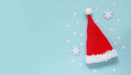 Creative Christmas composition. A greeting card, invitation, or flyer. Santa Claus hat and confetti in the form of snowflakes on a blue background. The view from the top.の写真素材