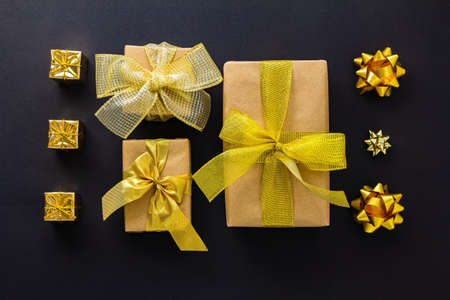 A set of gifts for Christmas, New Year, Birthday in gold and craft paper with different bows on a...