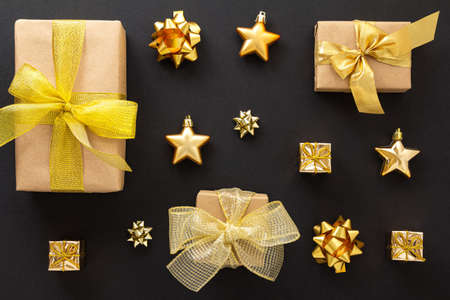 A set of gifts for Christmas and New Year in gold and craft paper with different bows and stars on a...