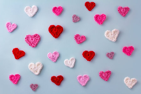A pattern of knitted hearts in pink, white and red on a blue background. The concept of Valentines...