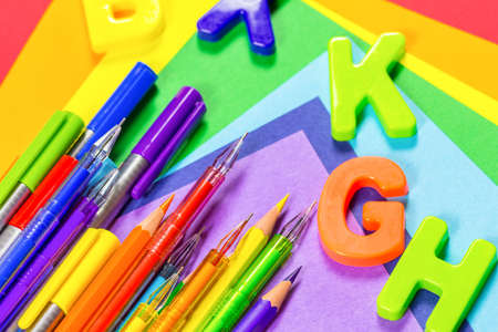 The concept of back to school. Pens, pencils and English letters lie on colored paperの写真素材
