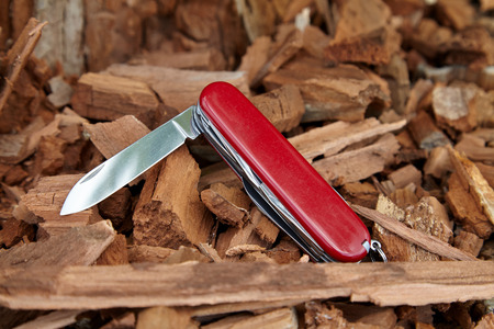 old scratched knife, open red penknife on the sawdustの写真素材