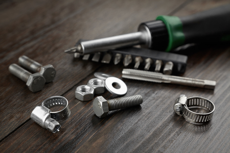 Mounting hardware made of metal. Screw, bolts and clamp on a wooden backgroundの写真素材
