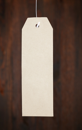 Paper tag on a woody background, branded clothing label with information about discountsの写真素材