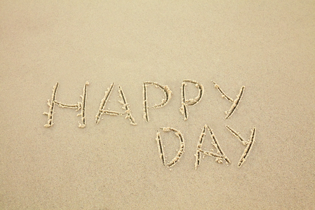 handwritten inscription happy day made in the sand, text on the beachの写真素材