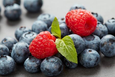 Macro photo of a bunch of wild berries in backlight, useful natural raspberry and blueberry berries close up on a stone background with bokehの写真素材