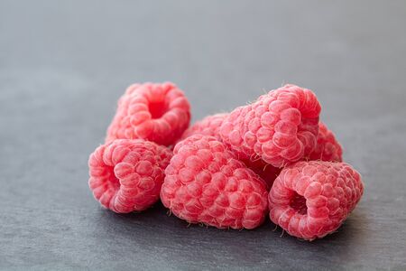 fresh ripe raspberry on a dark stone background, natural berry with natural backlight on black...