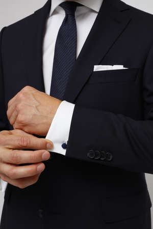 Close up of a man in suit. Man is holding cuff of suit