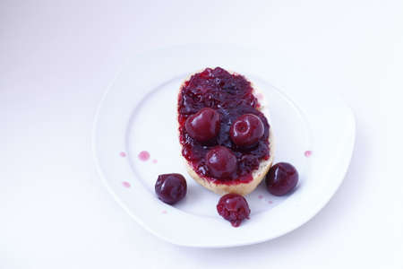half bun with cherry jelly on a white plate, isolatedの写真素材