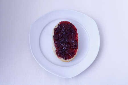 half bun with cherry jelly on a white plate, isolatedの写真素材