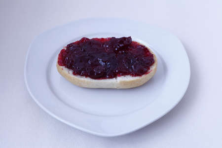 half bun with cherry jelly on a white plate, isolatedの写真素材