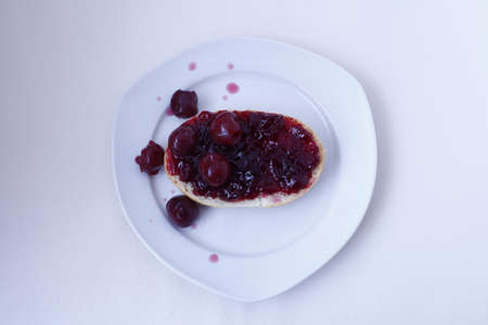 half bun with cherry jelly on a white plate, isolatedの写真素材