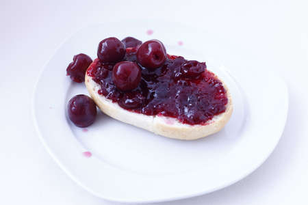 half bun with cherry jelly on a white plate, isolatedの写真素材