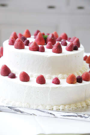 Three-tiered wedding cake with strawberries and raspberries.の写真素材