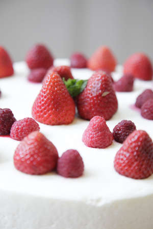 Three-tiered wedding cake with strawberries and raspberries, isolatedの写真素材