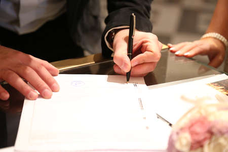 Close up of the hands of a bride signing the marriage contractの写真素材