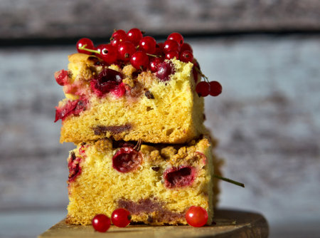 Piece of cake with red currant on a wooden background.の写真素材