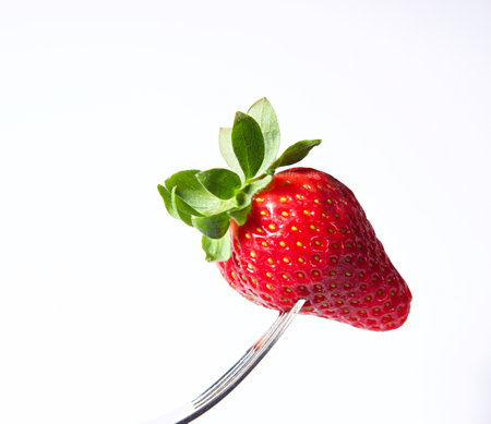 Strawberry on a fork isolated on white background, studio shotの写真素材