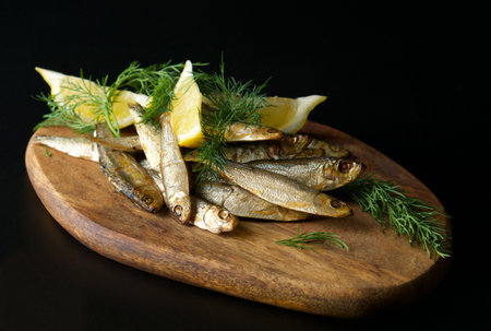 Fried sprats with lemon and dill on a wooden boardの写真素材