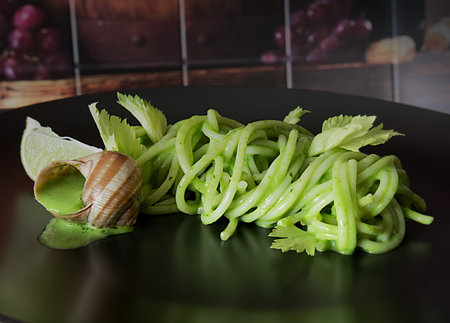 Spaghetti with zucchini, garlic and parsley on black plate