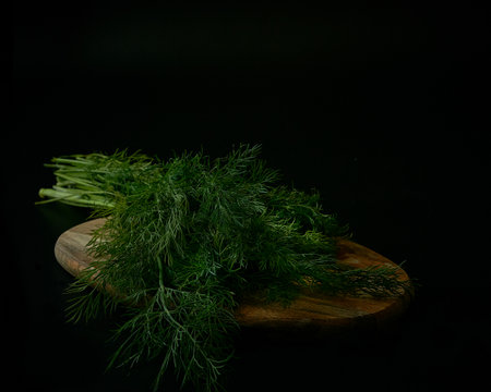 Fresh dill on a wooden cutting board on a black background.の写真素材