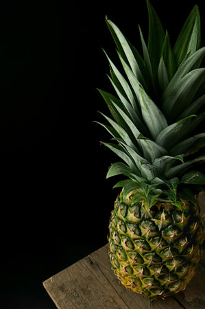 Pineapple on a wooden table on a black background. Copy space.の写真素材
