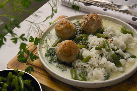 rice soup with meatballs and green beans on a wooden board.の写真素材
