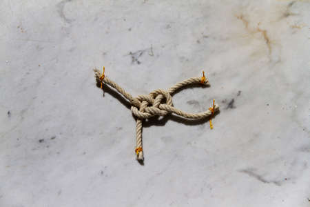 Basic sailor knot tied by yellow rope on marble
