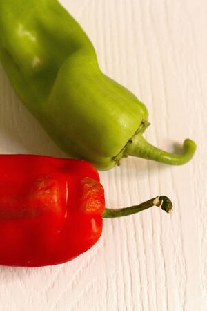 A red and a green pepper on a white surface texturedの写真素材