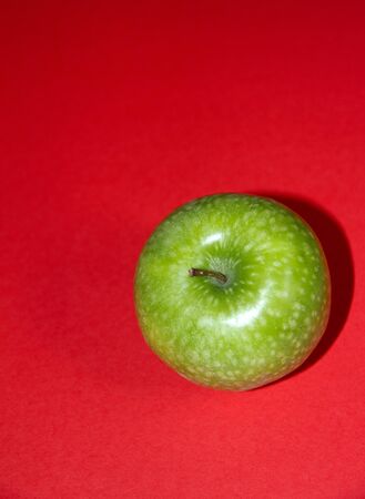 Green apple on red backgroundの写真素材