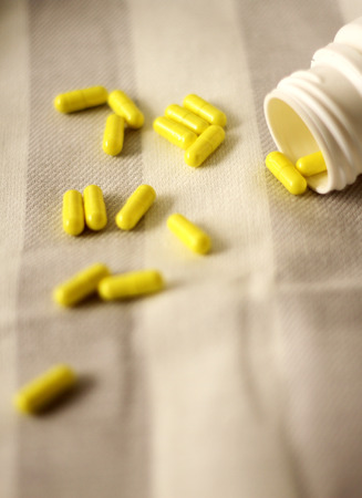 Yellow vitamins on a gray and white striped clothの写真素材